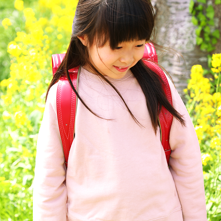 満面の菜の花の中を歩く池田屋ランドセルを背負う少女